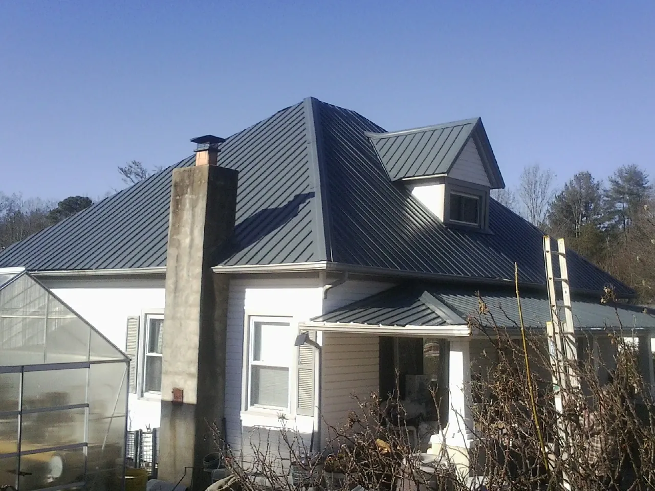 Dark blue standing seam metal roof on a white farmhouse with dormer — Slate & Tile Roof Repair by Roofing Brothers in Kanab