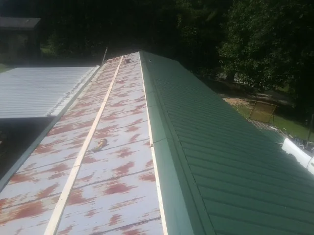 Old rusted panels beside newly installed green metal roofing — Wind Damage Roof Repair by Roofing Brothers in Kanab