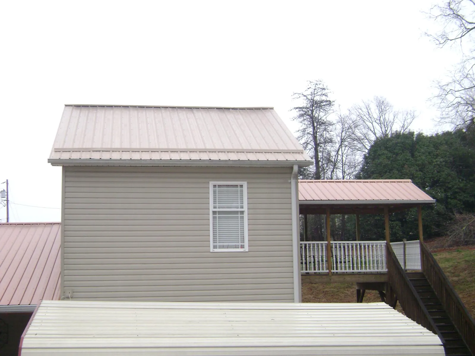 Tan metal roofs on a two story addition and attached porch, from a Roof Replacement job in Kanab
