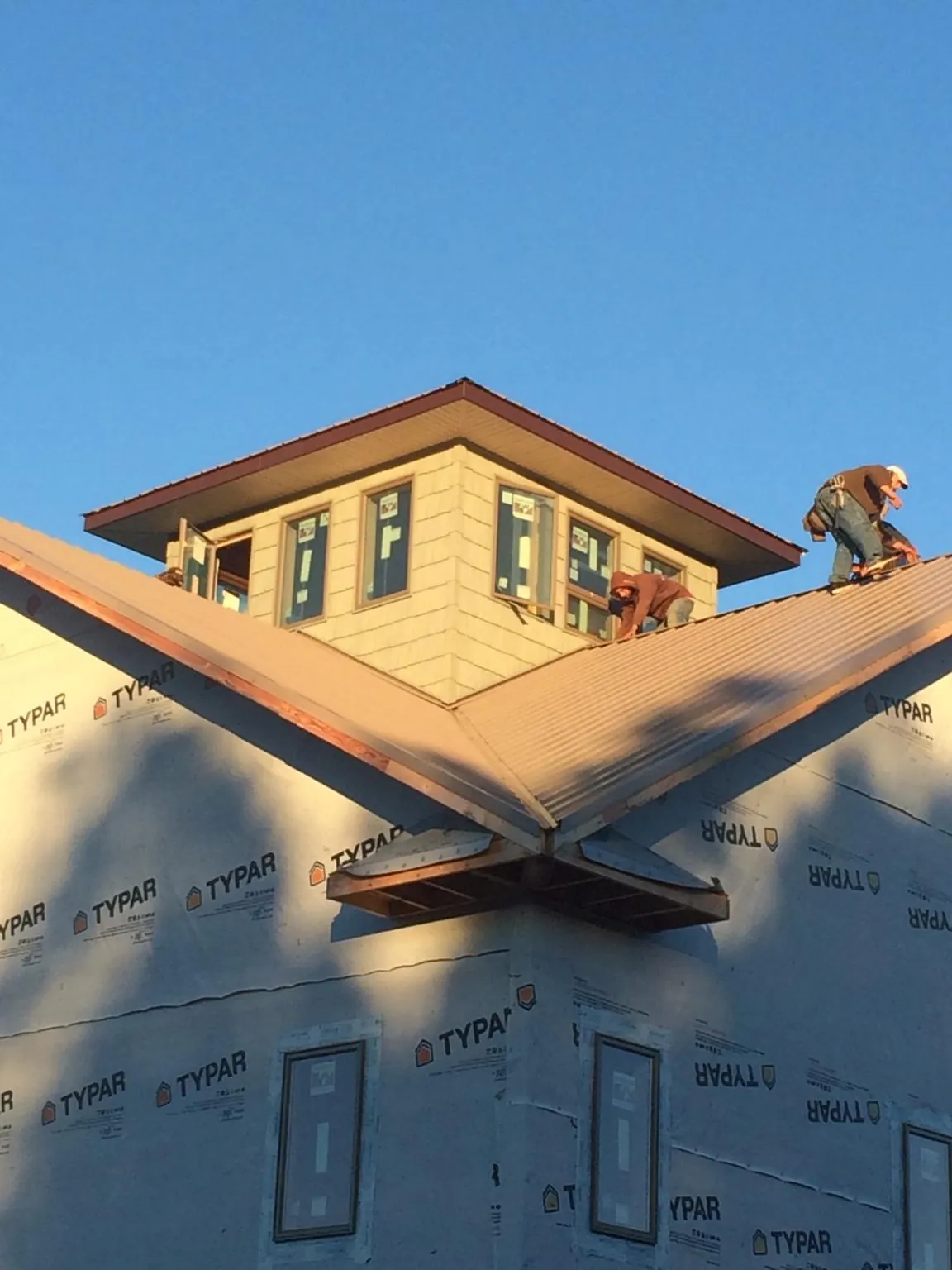 Roofers working around a rooftop cupola on a new metal roof at sunset — Roof Waterproofing in Kanab by Roofing Brothers